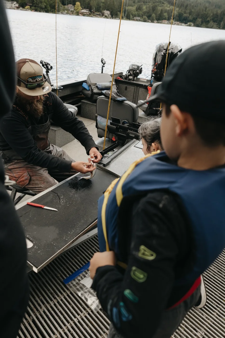 Outdoor instructor demonstrating how to clean a fish for youth participants