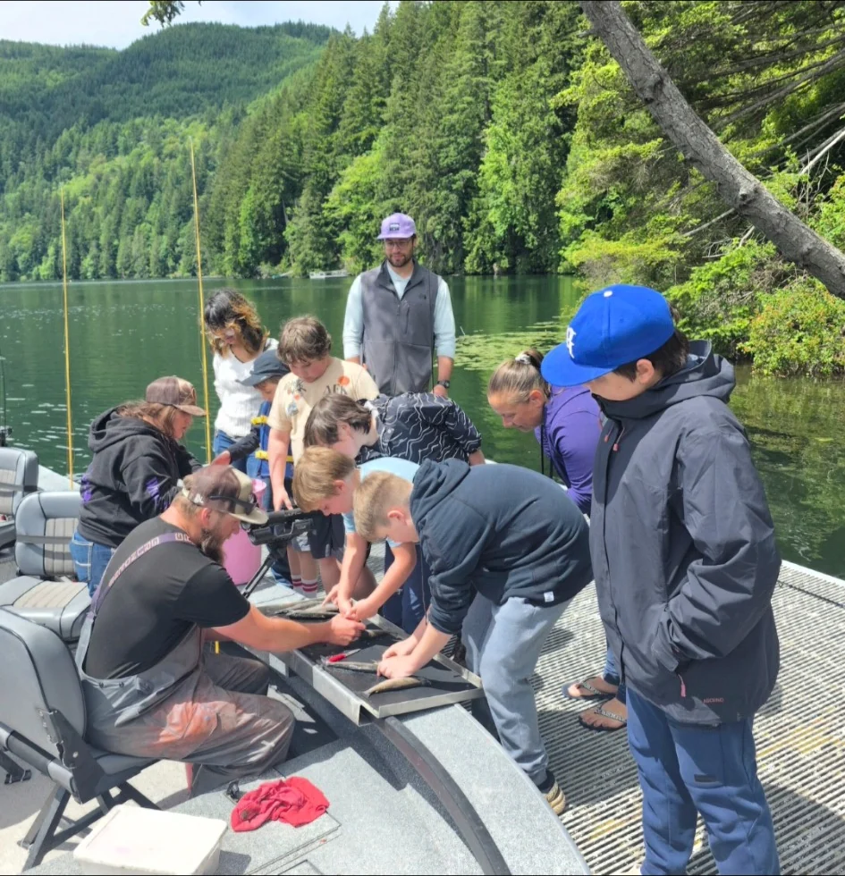 Youth gathered around an instructor learning how to clean fish
