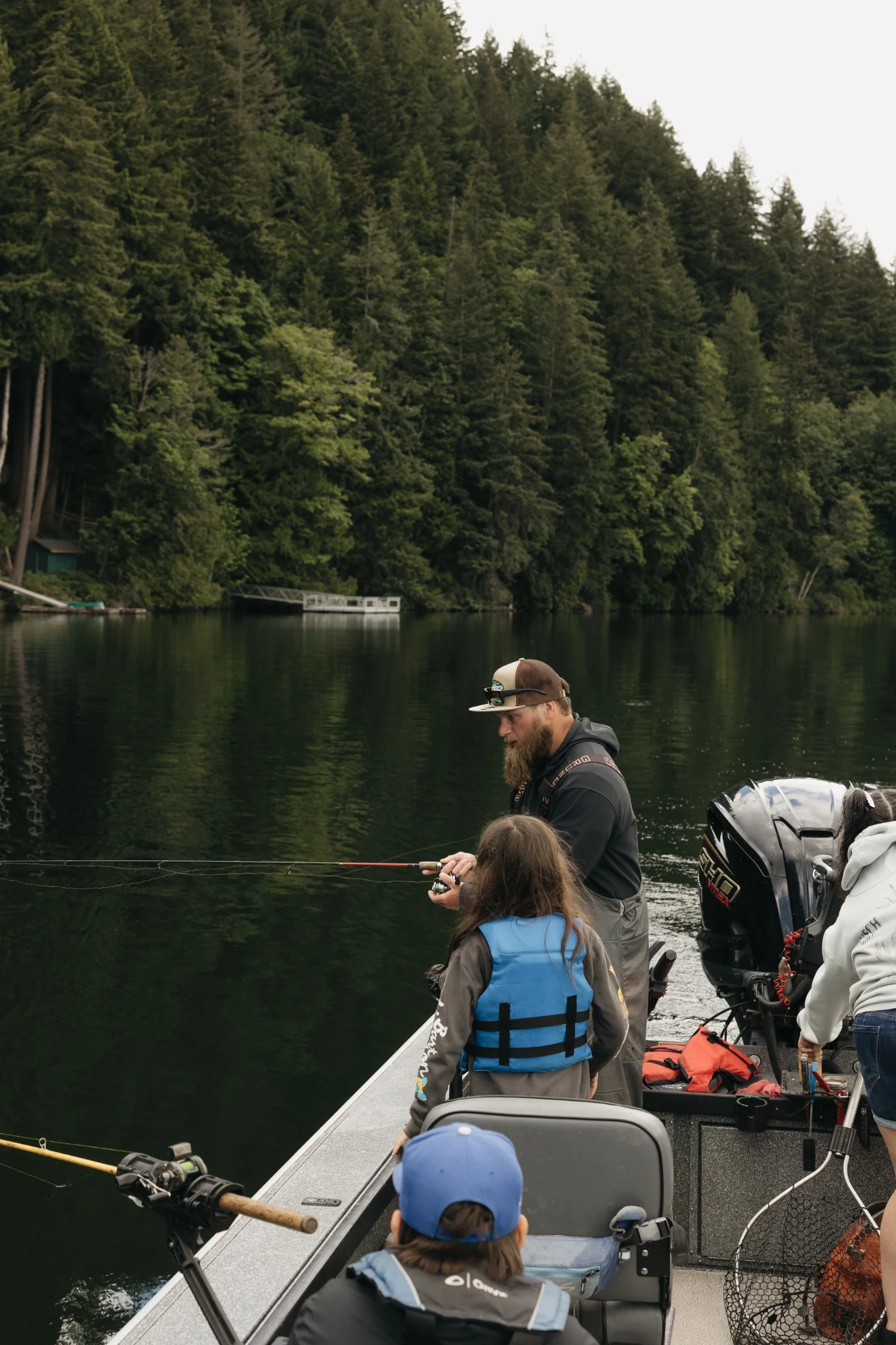 Youth learning to fish alongside an experienced guide on the lake