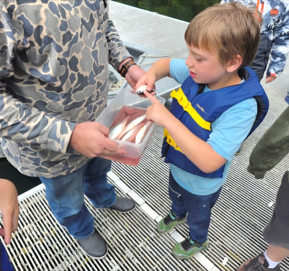 Young participant handling a fish during a cleaning demonstration